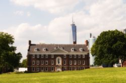 Edifici storici a Governros Island, New York - Una delle costruzioni di Governors Island dietro cui spicca la skyline di Manhattan con in primo piano il One World Trade Center alto 1776 piedi, ...