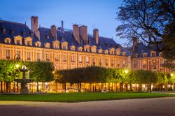 Fotografia notturna di Place des Vosges, i suoi alberi e gli eleganti palazzi dai mattoni rossi - © mdmworks / Shutterstock.com