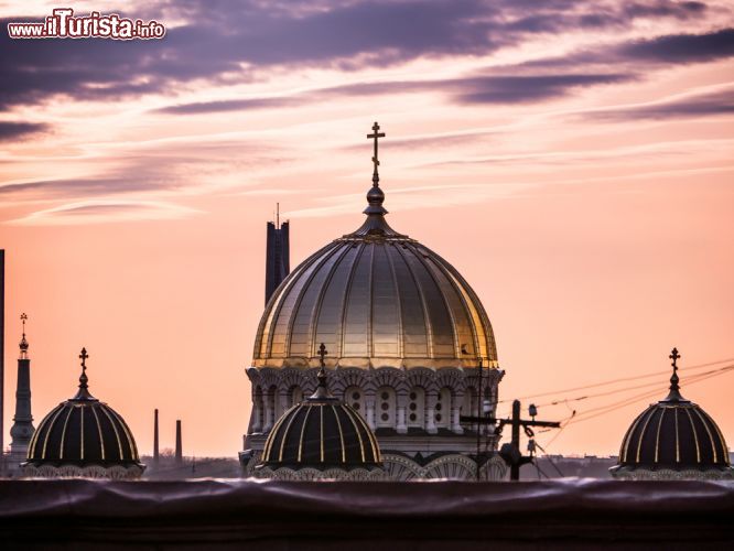 Immagine Un tramonto a Riga: il cielo colorato della capitale lettone e le cupole della Chiesa ortodossa della Natività di Cristo - © DolfinVik / Shutterstock.com