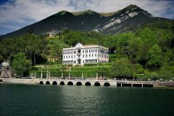 L'elegante facciata di Villa Carlotta fotografata da una barca emerge tra la rigogliosa vegetazione sulla riva del lago di Como - foto © www.villacarlotta.it