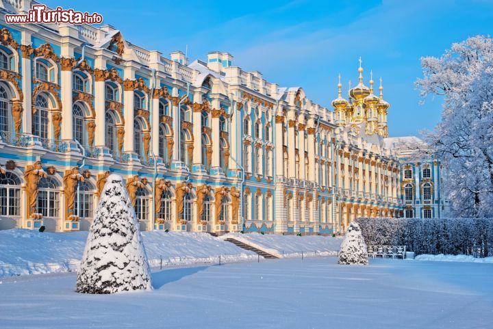 Immagine Palazzo di Caterina e Chiesa della Resurrezione a Pushkin, Russia. Sul grande giardino ricoperto dalla soffice neve bianca si affacciano l'ex dimora estiva degli zar e la bella chiesa della Resurrezione voluta proprio dall'imperatrice Caterina. Di particolare pregio le cupole dorate dell'edificio religioso - © Telia / Shutterstock.com