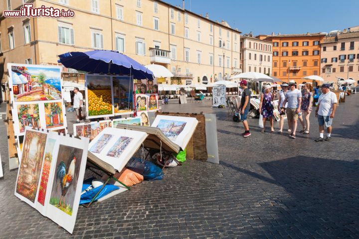 Immagine Panorama di Piazza Navona con bancarelle di dipinti e turisti, Roma, Italia. La maestosa piazza centrale di Roma ritratta in un'estiva giornata di sole con i turisti a passeggio e le bancarelle che vendono dipinti e quadri colorati - © Eugene Sergeev / Shutterstock.com