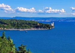 Il Golfo di Trieste in una bella giornata di sole, con il Castello di Miramare che si erge sul promntorio di Grignano. La città rimane nascosta alle spalle del promontorio