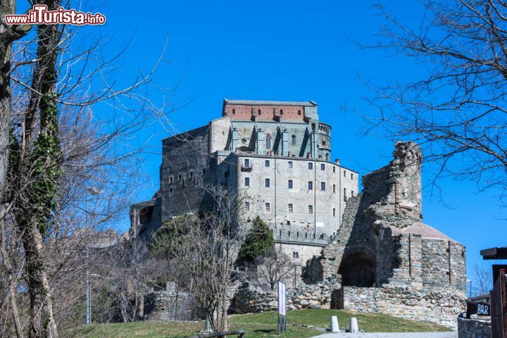 La Sacra di San Michele e Novalesa, Piemonte - Ha più di mille anni, ed anche se ora non è più possibile chiedere ad Umberto Eco se siano state proprio le sue forme e la sua posizione ad ispirarlo per il suo più famoso romanzo, Il Nome della rosa, la “Sacra” è una delle più suggestive abbazie al mondo, la madre di ogni luogo che si immagini tanto sacro quanto recondito. Dedicata a San Michele arcangelo, piemontese fino all’osso, con la sua struttura, svetta con imponenza all’imbocco della Val Di Susa sul monte Pirchiano. Insieme all’abbazia della Novalesa, che sorge poco oltre nella valle ed è di due secoli più antica della “sacra”, è un unicum che ancora oggi sa regalare orizzonti di meditazione e contemplazione. Mentre per tutti gli altri è una piacevole passeggiata e un viaggio nel tempo, in un ambiente incontaminato. Fondata, secondo la tradizione, su preesistenti edifici tardo-antichi, tra il 983 e il 987 da un nobile pellegrino alverniate, Ugo di Montboissier, divenne per tutto il Medioevo uno dei più importanti centri di cultura e spiritualità monastica europea lungo la via francigena. Da non perdere, oltre alla chiesa romanica, sono il museo, il portale dello Zodiaco, le rovine della Torre della Bell’Alda, custode di una terribile leggenda. Visitando l’Abbazia di Novalesa si può invece capire come abbiano vissuto per secoli i monaci e vederli al lavoro anche nella biblioteca che dal 1973 ha riaperto i battenti.

INFO: www.sacradisanmichele.com Chiuso lunedì tranne dal 15 luglio al 30 settembre. Fino al 16 ottobre c’è navetta dalla stazione ferroviaria di Avigliana (2 euro). Visite dalle 9.30 alle 18, chiuso pausa pranzo. Biglietto euro 8. Tel 011 939130