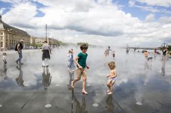 Bambini giocano tra le fontane dello Specchio d'Acqua di Place de la Bourse a Bordeaux, Francia - © Cloud Mine Amsterdam / Shutterstock.com