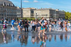 Ragazzi si divertono con i giochi d'acqua di Place de la Bourse a Bordeaux (Francia) - © dvoevnore / Shutterstock.com
