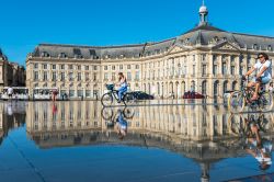 La gente ama attraversare lo Specchio d'acqua posto di fronte a Place de la Bourse anche con la bici o il monopattino. Siamo a Bordeaux, in Francia - foto © dvoevnore / ...