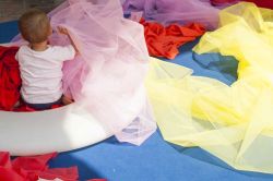 Un bambino gioca con dei tessuti, tra colori e esperienze tattili al Museo dei Bambini di Milano - © Elena Valdre / www.muba.it