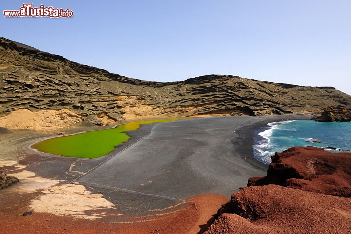 Charco de los Clicos, isola di Lanzarote - Questo luogo alieno si trova nel comune di Yaiza, a sud dell'isola di Lanzarote , nei pressi del villaggio di El Golfo, che oltretutto merita una visita anche solo godere del pesce fresco che viene servito dai ristoranti della zona! La laguna si trova proprio accanto alla spiaggia che porta lo stesso nome del villaggio, ed è formata da acqua di mare che filtra attraverso al terreno sabbioso-ghiaioso. E veramente uno spettacolo naturale che mette in evidenza il contrasto della spiaggia di sabbia nera , il cielo blu , l'azzurro del mare, e le tinte che vanno dal verde smeraldo al giallo paglierino della laguna!
Il suo vero nome è Charco de los Clicos, ma tutti lo chiamano il lago verde, o anche il lago giallo, a secondo della tinta predominante. Il colore dipende sia da una alga particolare (verde), da qualche minerale ed anche dal riflesso delle pareti di roccia, che a seconda della luce, danno un tinta più o meno giallastra.
Charco de los Clicos è dichiarata come area protetta, quindi il bagno nella laguna è vietato, quindi godetevi la spiaggia antistante e fate il bagno nel mare, ovviamente se avete il coraggio di affrontare le onde, spesso vigorose! - Foto: es.enjoylanzarote.net 