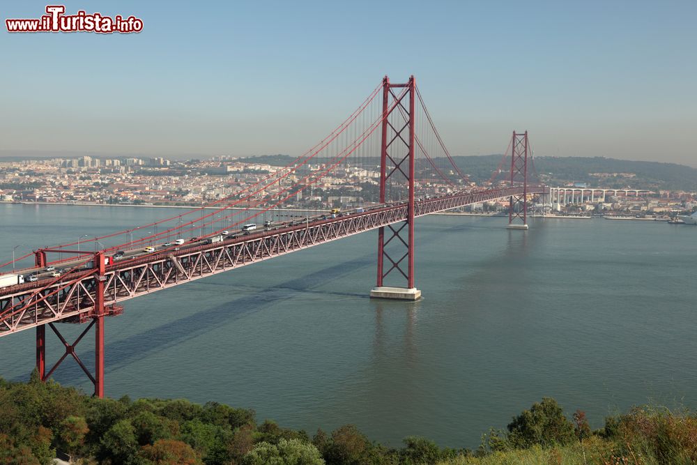 Immagine Il ponte sospeso 25 de Abril sul fiume Tago a Lisbona, Portogallo . Chiamato anche come il Golden Gate di Lisbona, è uno dei simboli della capitale del Portogallo. Questa foto è stata scattata dal giardino del Santuario Cristo Rei, ad Almada sulla sponda meridionale del fiume Tago.