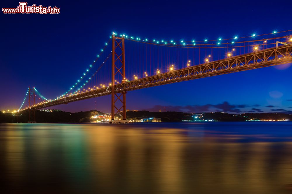 Immagine Vista notturna del ponte 25 Aprile, il piu famoso di Lisbona sul fiume Tago. Con una campata unica di oltre 1 chilometro, il ponte è stato al momento della sua creazione il più lungo d'Europa