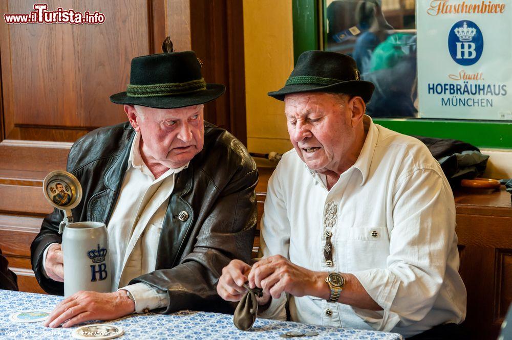 Immagine Due uomini seduti a un tavolo della Hofbrauhaus, la famosa birreria del centro di Monaco di Baviera (Germania) - © cornfield / Shutterstock.com