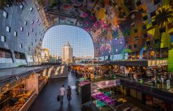 Shopping tra le bancarelle del Markthal il vasto mercato di Rotterdam. Lasciatevi accarezzare dai profumi e curiosate attorno. Tutto il piano terra è dedicato al mercato indoor. ...