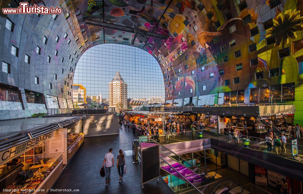 Immagine Shopping tra le bancarelle del Markthal il vasto mercato di Rotterdam. Lasciatevi accarezzare dai profumi e curiosate attorno. Tutto il piano terra è dedicato al mercato indoor. Come spesso accade nei paesi nordici, tutto è molto ordinato e ben organizzato. La struttura, ipermoderna, regala spazi ben delimitati, geometrici, ma rallegrati dai colori della frutta e dal vocio della gente. Se quello che cercate in un viaggio è il contatto con i luoghi e le persone, il modo migliore è quello di fare visita al suo mercato. - © nattawit.sree / Shutterstock.com