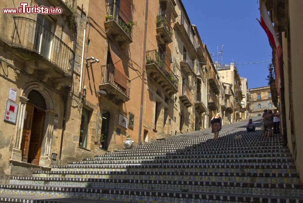 Immagine Gente sulla scalinata in maiolica di Santa Maria del Monte a Caltagirone, provincia di Catania, Sicilia. Costruita nel 1608 a sbalzi, 250 anni più tardi la scalinata è stata unificata su progetto dell'architetto Salvatore Marino diventando così rettilinea.
- © trolvag, CC BY-SA 3.0, Wikipedia