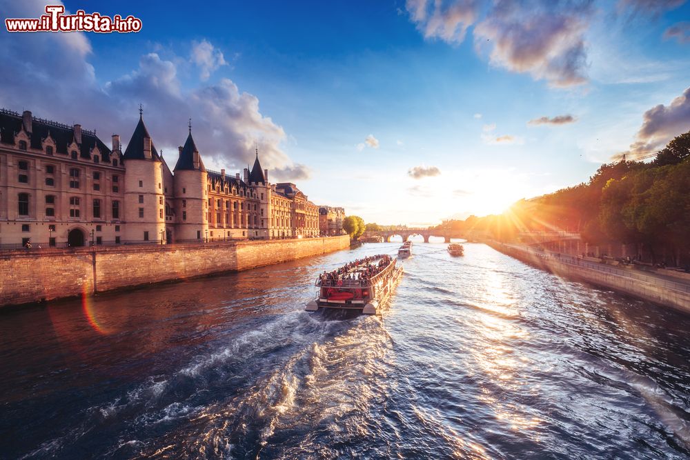 Immagine Tramonto sul fiume Senna a Parigi con la Conciergerie e il Pont Neuf, Francia. Di giorno o alla sera, la crociera sul fiume regala una delle prospettive più suggestive della città.