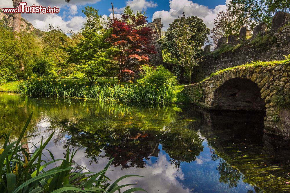 Immagine Un pittoresco angolo del Giardino di Ninfa, Cisterna di Latina (Lazio). Un ruscello, un antico ponte in pietra e alberi: ecco gli elementi di questo suggestivo parco diventato monumento nazionale per la sua storicità.