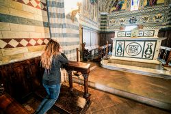 Una ragazza prega nella chiesa del castello di Brolio, provincia di Siena (Toscana) - © arkanto / Shutterstock.com