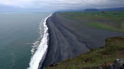 Una vista panoramica dalla cima del promontorio di Dyrhólaey sull'enorme spiaggia nera ai suoi piedi, lungo la costa meridionale dell'Islanda.
