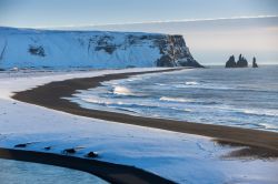 La spiaggia vulcanica di Reynisfjara in inverno. Questa suggestiva spiaggia islandese è compresa tra il promontorio di Dyrhólaey e il Monte Reynisfjall, visibile in questa foto.
 ...