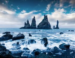 Vik i Myrdal: faraglioni nel mare davanti alle scogliere del Monte Reynisfjall, nei pressi del promontorio di Dyrholaey (Islanda).