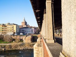 Le colonne del Ponte Coperto sul Ticino a Pavia, Lombardia. Sullo sfondo, veduta della città e del duomo al tramonto - © KrimKate / Shutterstock.com