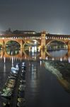 Uno scorcio by night del Ponte Coperto di Pavia con il fiume Ticino e le imbarcazioni ormeggiate.
