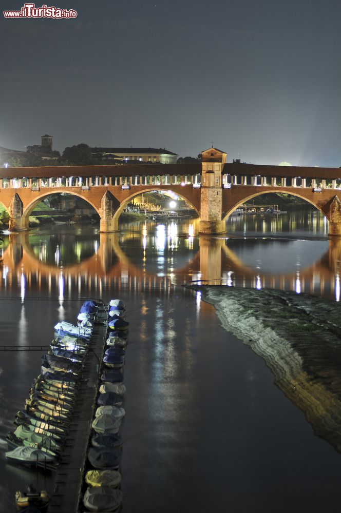 Immagine Uno scorcio by night del Ponte Coperto di Pavia con il fiume Ticino e le imbarcazioni ormeggiate.