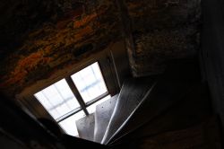 Interno della torre civica di Bruges, Belgio: particolare delle ripide scale in legno e del muro in mattoni - © Kanda K / Shutterstock.com
