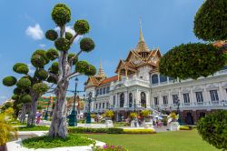 Giardini al Grand Palace di Bangkok, Thailandia, con turisti e fedeli in visita.
