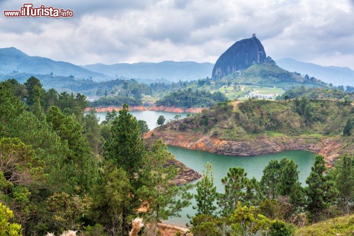 La Piedra del Peñón (o Penol), Colombia - Esiste una roccia a Guatapé, nel dipartimento di Antiochia in Colombia, che ogni anno viene visitata da migliaia e migliaia di turisti provenienti da tutto il mondo: è la Piedra del Peñon (nota anche come "Il Peñon" o "El Peñón de Guatapé"). Si tratta di un blocco monolitico che raggiunge i 200 metri di altezza ed in passato è stato anche meta di pellegrinaggio. Scopriamolo più da vicino.

Salire 650 gradini per una vista mozzafiato, 740 per la vetta
La Piedra del Peñon può essere definita una montagna (appartenente alla Cordigliera delle Ande) dalle origini millenarie e composta da rocce minerali, in cui prevalgono il quarzo, la mica ed il feldspato. Sorge a ridosso della diga idroelettrica di Guadapé e si staglia a guardare tutta la città. Già anticamente la Piedra fu vista come un luogo di culto e pellegrinaggio, tanto che si decise di costruire dei gradini (ben 740 in totale, 650 per il primo punto di osservazione!) in cemento e legno lungo tutta la sua facciata, per consentire a chiunque di poter raggiungere la vetta e godere di una fantastica vista su tutti i villaggi limitrofi. Nonostante la scalata non indifferente sono in tantissimi i turisti che ogni anno si riversano a Guadapé per ammirare il Peñon, tanto che quest'ultimo è diventato una vera e propria superstar già dal 1954, quando per la prima volta fu tentata e riuscita un'ascesa alla cima, con attrezzature semplicissime, da Don Luis Edoardo Villegas.

Come arrivare
Per arrivare al Peñon bisogna innanzitutto raggiungere la Colombia. Si può decidere di fermarsi a Medellìn, capoluogo di Antiochia, e poi da lì percorrere quasi 86 chilometri  in auto per arrivare a Guatapé, oppure alloggiare direttamente a Guatapé, che oggi è diventato un sito turistico colombiano di notevole importanza, ed arrivare al sito della "Piedra" in pochi minuti, in taxi, in autobus o in bici. Una volta arrivati alle falde della roccia, bisognerà pagare un biglietto per la "scalata", che ammonta a circa 10 mila pesos colombiani (corrispondenti più o meno a 4 euro). Dopo i primi 650 gradini si potrà trovare una zona di ristoro, con bar, caffetteria e negozi di souvenir, poi, se lo si desidera, si potrà tentare di raggiungere la vetta.- © Jess Kraft / Shutterstock.com 