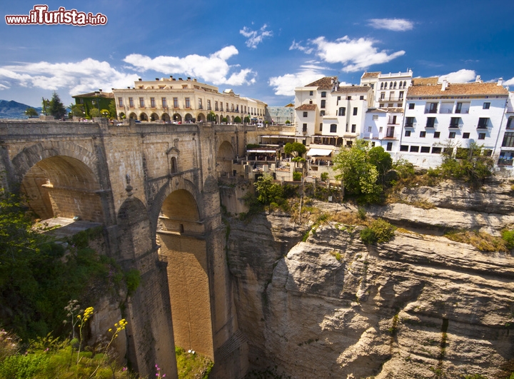 Vista panoramica di Ronda in Andalusia, Spagna - Situata nell'entroterra dell'Andalusia, non distante dalle spiagge di Marbella, Ronda offre scenari ed montagna e tutto il calore della Spagna. La città sorge nei pressi di una profonda gola (tajo) scavata dal torrente Guadalevín,  e che si può ammirare dall'ardito Puente Nuevo, costruito alla fine del 18° secolo. Ronda è un gioiellino della Spagna, di quella regione chiamata Serrania. ed è un piacere da visitare con le sue vie che ancora mostrano l'influenza della dominazione araba. Da non perdere la sua Plaza de Toros, considerata la più antica di tutta la Spagna, che include al suo interno uno spazio dedicato a museo, ed il Ponte Arabo il migliore di del genere nella penisola iberica.