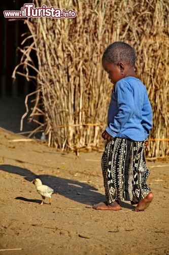 Un bambino malgascio gioca con un pulcino