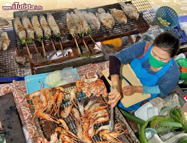 Cucina pesce al mercato galleggiante di Bangkok