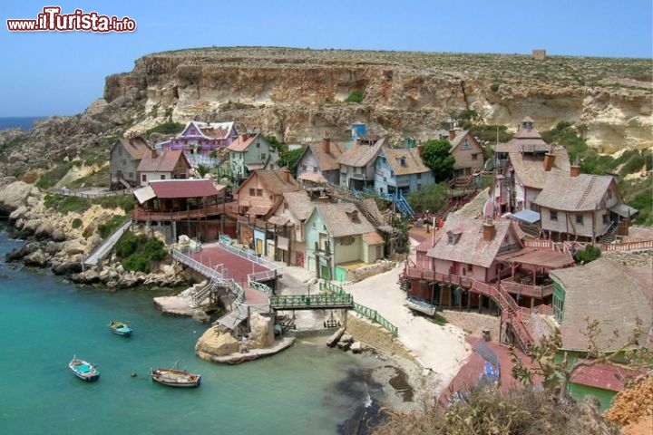 Popeye Village (Sweethaven Village), Anchor Bay, Malta. Il Popeye Village di Malta, conosciuto anche come Sweethaven Village, non nacque come parco dei divertimenti: era il set cinematografico del film Popeye-Braccio di Ferro, interpretato da Robin Williams per la Paramount e la Disney. La costruzione era cominciata nel giugno del 1979, e le riprese cominciarono sei mesi dopo: l’azione si svolgeva tra una ventina di edifici in legno un po’ sgangherati, che riproducevano un tipico borgo di pescatori. La location certamente aiuta, perché il paese di Braccio di Ferro si trova a Malta, incastonato nella Anchor Bay, e il mare e le scogliere sono tutt’altro che finte. Dopo le riprese del film, che non fu propriamente un successo, la scenografia divenne un museo a cielo aperto visitabile 7 giorni su 7, a cui si aggiunsero attrazioni per famiglie e una ricca programmazione di eventi. I destinatari ideali sono i bambini, ma anche i genitori possono apprezzarlo per un’intera giornata, accompagnando i piccoli sugli scivoli d’acqua, sguazzando in una delle piscine o semplicemente prendendo il sole. Non fatevi mancare un tatuaggio da Popeye sul bicipite e un buon hamburger con gli spinaci, poi, una volta a casa, date uno sguardo allo specchio. Non vedete qualche muscolo in più?
Per maggiori informazioni visitate www.popeyemalta.com.