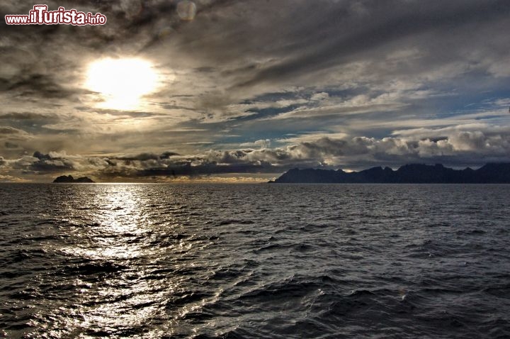 Le Lofoten e isola di Varoy - Questa immagine è stata scattata dal traghetto che da Bodo raggiunge Moskenes. Al tramonto il mare antistante le Lofoten si accende di un colore dorato intenso, mentre il cielo è solcato da molte nuvole che si rincorrono veloci.