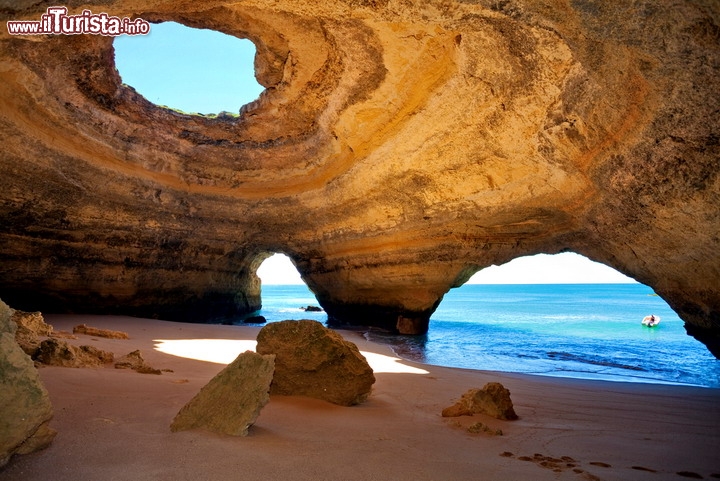 Grotta marina della spiaggia di Benagil in Algarve, Portogallo - E' uno dei luoghi più magici dell'Europa, sicuramente uno dei paesaggi più belli del Portogallo: parliamo della grotta di Benagil, che si trova ad appena 150 metri dell'omonima spiaggia, posta a circa metà strada tra le cittadine di Carvoeiro e Armacao de Pera. L'ingresso è però possibile unicamente con una barca, oppure a nuoto dalla spiaggia. Si tratta di una cavità formatasi per l'erosione da parte delle onde dell'Oceano Atlantico, che bagna le coste dell'Algarve, il sud del Portogallo. Nella stagione invernale la costa alta di Benagil viene flagellata da marosi e cavalloni che hanno eroso in modo spettacolare le arenarie ed i conglomerati dalle calde tinte arancioni. Il tetto della grotta è parzialmente crollato, formano una apertura circolare che illumina l'interno. La caverna possiede due ingressi ed in caso di mare calmo è un luogo perfetto in estate per fare dei rilassanti bagni, in una cornice unica al mondo  - © tagstiles.com - S.Gruene / Shutterstock.com 