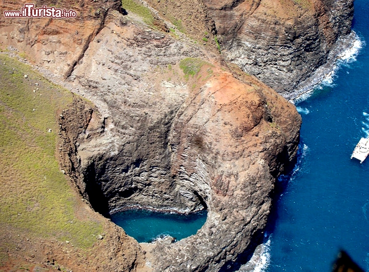 Open Ceiling Cave, Kauai, Isole Hawaii  - Lungo la Na Pali Coast, è particolarmente scenografica grazie all’incontro tra il mare e il cielo, separati dall’orlo scuro della grotta. Questa imponente struttura di pietra lavica, plasmata dai venti e dalle onde nel corso dei secoli, è un rifugio naturale in cui gli hawaiani sostavano con le canoe durante le battute di pesca. Non sappiamo come venisse chiamata dagli indigeni, ma Open Ceiling Cave, che significa “Grotta dal soffitto aperto”, rende bene l’idea: chi si insinua con la barca all’interno della grotta e ne raggiunge il centro si troverà col cielo aperto sulla testa, sentendosi protetto ma allo stesso tempo accarezzato dal sole. Proprio il sole, sfiorando l’acqua, le dà una colorazione turchese irreale e proietta magici giochi di luce sulle pareti rocciose.