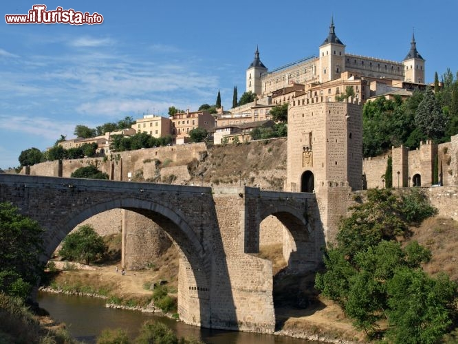 Alcazar, il famoso castello di Toledo, Spagna - La sua superba posizione, sulle rive del fiume Tago, che poi andrà a sfociare in Portogallo a Lisbona, era già nota ai romani che qui posero una prima costruzione nel 3° secolo. Il primo castello spagnolo risale invece all'11° secolo, quando il primo fortino venne ampliato da Alfonso VI di Castiglia. Il monumentale aspetto odierno del Castello di Toledo, fu impresso però sotto il regno di Carlo I di Spagna, che affidò l'opera al pragmatismo di Alonso de Covarrubias, che creò questo edificio dalle forme compatte e regolari. Durante la Guerra Civile Spagnola il Castello dell'Alcazar venne pesantamente danneggiato, dato che era la sede del comando Repubblicano che fu sconfitto dal generale Franco. Ricostruito nelle sue forme originali, ospita oggi la Biblioteca della Castiglia - La Mancia  - © aguilarphoto / Shutterstock.com