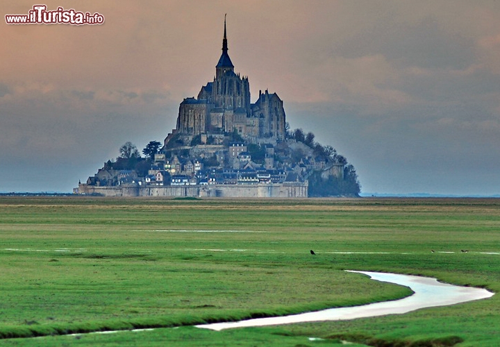 Mont Saint-Michel, Normandia, Francia - Patrimonio dell’Umanità dal 1979, il castello medievale di Mont Saint Michel (vedi galleria foto) è arroccato su un isolotto al largo della costa francese settentrionale, sulla foce del fiume Couesnon. Il santuario e il paesaggio circostante fanno parte di un’unica meravigliosa ambientazione, mutevole secondo il respiro del mare: all’alzarsi e abbassarsi della marea, lo scoglio viene inghiottito e poi liberato dalle onde, facendo sì che il castello sia raggiungibile via terra solo in certe ore della giornata. Il nome completo sarebbe “Mont Saint-Michel au péril de la mer”, ovvero “Monte San Michele in pericolo del mare”, ma non si può certo dire che il mare, qui, rappresenti un pericolo: quel lento scivolare dell’acqua è la fortuna di un sito già splendido. 