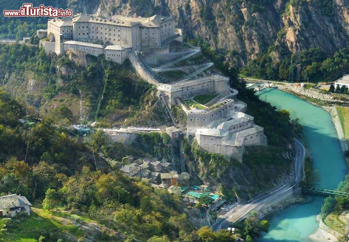 Fortezza di Bard, Valle d'Aosta, Italia - Il Forte di Bard è un magnifico complesso monumentale che si erge all'inizo della Valle d'Aosta, ponendosi come insuperabile sbarramento militare. Probabilmente durante il mediovevo qui sorgeva un castello, di cui rimangano modeste tracce, ma oggi il Borgo di Bard appare come una piazzaforte imponente, tra le più spettacolari del mondo, fedele al suo aspetto originale di inizio Ottocento. Si sviluppa su vari livelli, a partire da una quota di 467 metri, che digradano fino a quota 400 con vari fabbricati. Guardandola dall'esterno abbiamo, a partire dalla cima, l'Opera Carlo Alberto e l'Opera di Gola, gli edifici racchiusi dalla cinta muraria, poi a metà del pendio troviamo l'Opera Vittorio, e più in basso l'Opera Mortai e l'Opera Ferdinando. Se vi spaventa una visita con troppa salita, vi ricordiamo che esitono dei magnifici ascensori panoramici che dalla cittadina di Bard salgono alla fortezza.