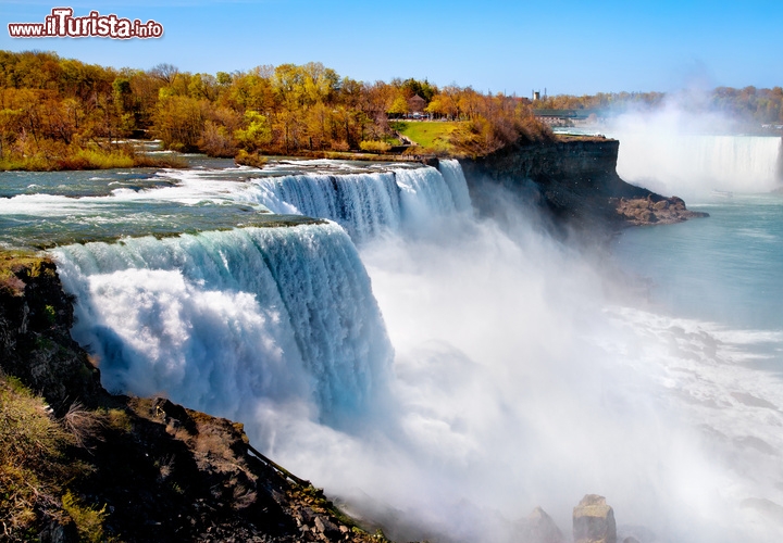 Cascate del Niagara, Ontario, Canada/New York, USA - Le cascate più famose del Nord America, e probabilmente del mondo, si trovano a cavallo tra Canada e Stati Uniti, lungo il corso del fiume Niagara. La discesa comincia in territorio canadese con la Horseshoe Falls e termina negli Stati Uniti, dove le Bridal Veil Falls rappresentano l’ultima e più modesta caduta. Un salto complessivamente sensazionale, perché le Niagara Falls, pur modeste in altezza (53 m) hanno una portata di 1,8 milioni di litri d’acqua al secondo, che precipitano sollevando una nube di vapore screziata dal sole. Il complesso di tre cascate è apprezzabile da qualsiasi angolazione e in ogni momento della giornata, essendo dotato di un imponente sistema di illuminazione, e lo si può ammirare anche di notte dalla cima della vicina Skylon Tower, costruita sul lato canadese, non distante dal centro di Toronto. 