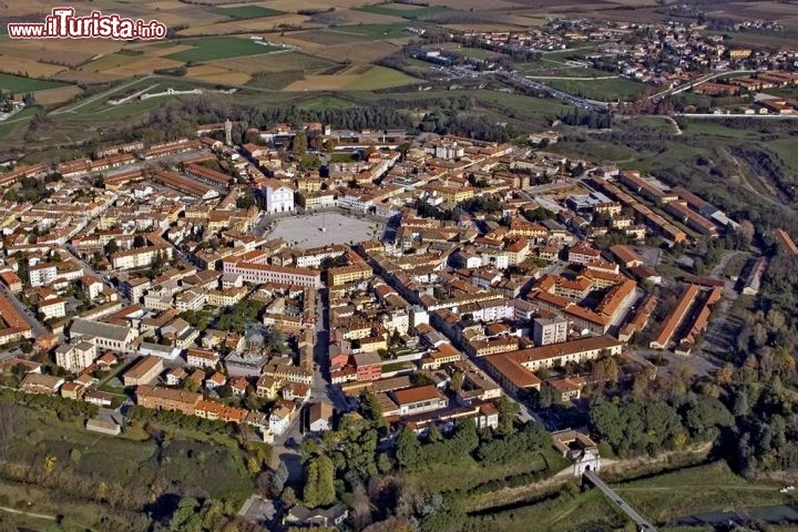 La città murata di Palmanova, Friuli
E' la città fortezza più famosa del Friuli, ma èanche nota in tutto il mondo per la sua particolare pianta poligonale. Palmanova nacque nella sua attuale, stabiliante forma alla fine del 16° secolo, quando i Veneziani vollero creare una fortezza inespugniabile al confine settentrionale dei suoi territori. Un opera di ingegneria militare tra le più evolute dell'epoca, capace di resistere agli attacchi delle armi da fuoco più pesanti del periodo rinascimentale-barocco. Oggi Palmanova conserva intatto il suo fascino con le mura esterne “stellate” trasformate in verdi giardini, e il centro storico con una pianta radiale, che si dirama dalla piazza centrale, Piazza Grande, di forma perfetta esagonale. Su questa magnifica piazza si trova il Duomo ed il Civico museo storico di Palmanova - © Turismo FVG (Ecoplane)