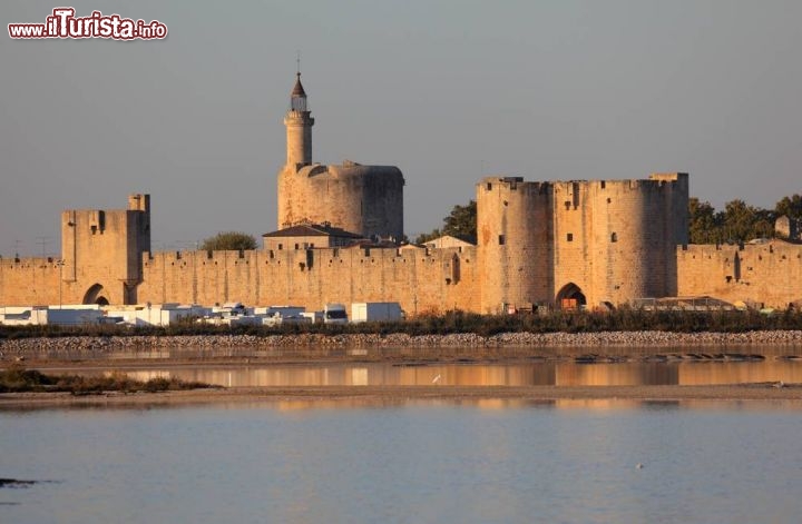 Città fortificata di Aigues Mortes in Camargue, Francia
Anticamente Eaux-Mortes per via delle lagune e delle acque stagnanti, il borgo fortificato di Aigues Mortes fu fondato da San Luigi IX°, re di Francia, che fece costruire tra il 1240 e il 1249 la tour de Costance e un porto in acque profonde da dove partì per la 7^ e 8^ crociata. La cinta fortificata è uno degli esempi più importanti e completi di architettura militare del XIII° secolo. E' a pianta quadrilatera di circa 500x300 metri, aperta da 10 porte, cinque delle quali fiancheggiate da torri cilindriche e da altre merlate fra cui spicca quella di Costance, possente mastio di 40 metri d'altezza x 22 di diametro e con mura spesse 6 metri. Dalla terrazza di quest'ultima si gode un magnifico panorama sulla città che sorge sul canale Sète-Rodano al limite occidentale della Camargue a circa 6 km dal mare.
