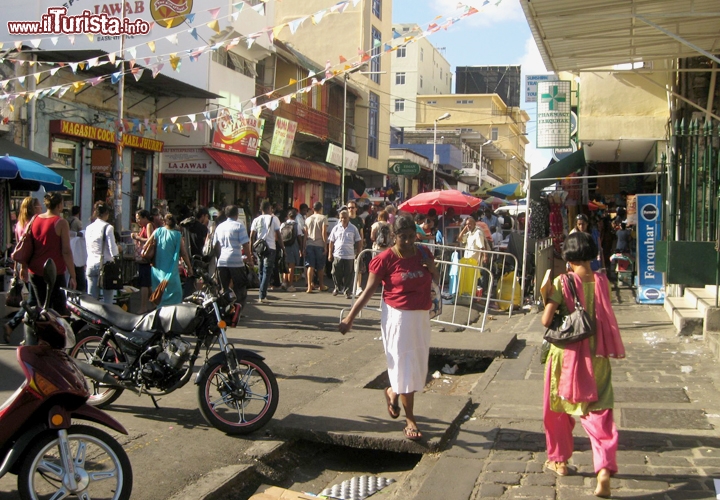 Una strada di Port Louis la Capitale di Mauritius, accanto al mercato, affollata di passanti, biciclette, auto, moto e i carretti dei venditori di bibite.