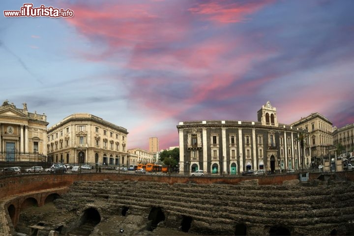 Anfiteatro romano di Catania, Sicilia - L’anfiteatro romano che sorge nel centro di Catania, conservato solo in parte, è compreso nel Parco Archeologico greco-romano della città. Quando fu realizzato, nel II secolo d.C., doveva trovarsi ai margini del centro abitato, sul fianco del colle Montevergine. L’eruzione vulcanica del 252-253 lo danneggiò ma non lo distrusse, e nei secoli successivi fu usato per innumerevoli scopi: il re ostrogoto Teodorico, ad esempio, ne ricavò del materiale per la costruzione di abitazioni, mentre in età medievale Ruggero II di Sicilia sottrasse altre pietre per la Cattedrale di Sant’Agata. © VLADJ55 / Shutterstock.com