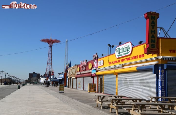 Immagine Il molo di Coney island con uno dei ristoranti Nathans dove gustare i migliori hot dog della Grande Mela. Sullo sfondo una giostra del famoso Luna Park che si trova sulla penisola a sud di Brooklyn - © Leonard Zhukovsky / Shutterstock.com