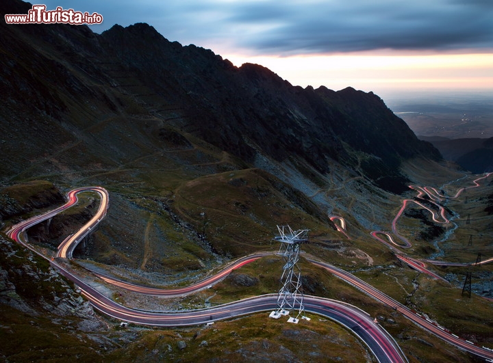 Transfagarasan la tortuosa strada dei Carpazi in Romania - Questa spettacolare foto in notturna, grazie ad una lunga esposizione che evidenzia le scie dei fanali lungo la strada, ci rivela il paercorso serpeggiante della strada più famosa, tra i motociclisti, di tutta la Romania: si chiama Transfagarasan (DN7C), ma è anche conosciuta con il soprannome di "Follia di Ceaușescu", dato che venne costruita tra il 1970 e il 1974 per volere del dittatore rumeno. La strada, inizialmente un percorso militare, letteralmente si arrampica lungo le pendici dei Carpazi Meridionali, fino a tocchare una ragguardevole altitudine di 2.034 metri sul livello del mare. E' lunga 90 km e rimane aperta solamente da giugno ad ottobre. Lungo il suo divertente percorso ci si può deliziare dei paesaggi montani, e del scenografico lago di Bâlea e l'omonima cascata - © Andrei Pop / Shutterstock.com 