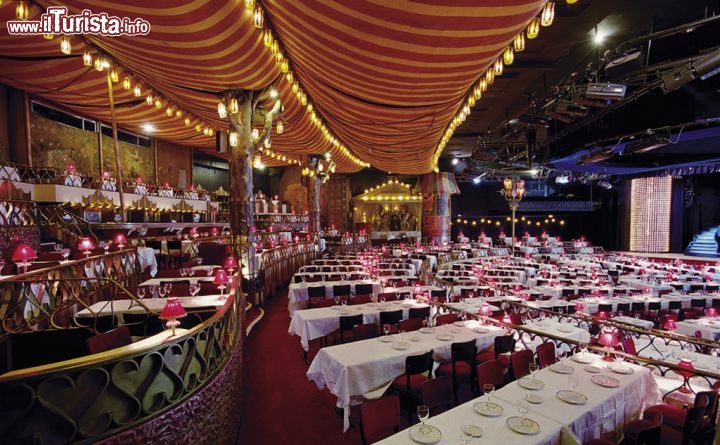 Immagine I tavoli della platea del Moulin Rouge a Parigi - Una serata al Moulin Rouge non è per tutte le tasche! Se lo spettacolo in se ha un prezzo in genere inferiore ai 100 euro (si prala di 80-90 euro), la cena può risultare piuttosto costosa, anche una settantina di euro, cui si devono aggiungere i costi di eventuali extra, dalla foto con le ballerine ai calici e bottiglie di champagne - © Henri Clement / Paris Tourist Office