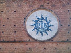 Monogramma di Cristo (anche detto Monogramma Bernardiano) sualla facciata del Palazzo Pubblico a Siena. Realizzato da da Battista di Niccolò e Turino di Sano nel 1425.